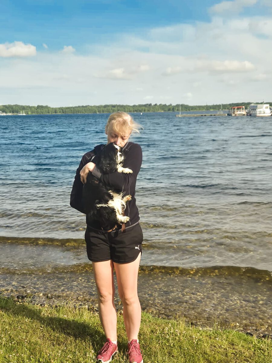 Eien Frau mit ihrem Hund im Arm am See