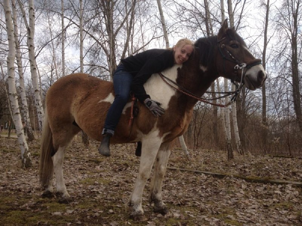 Eine junge Frau auf einem kleinem bunten Pferd